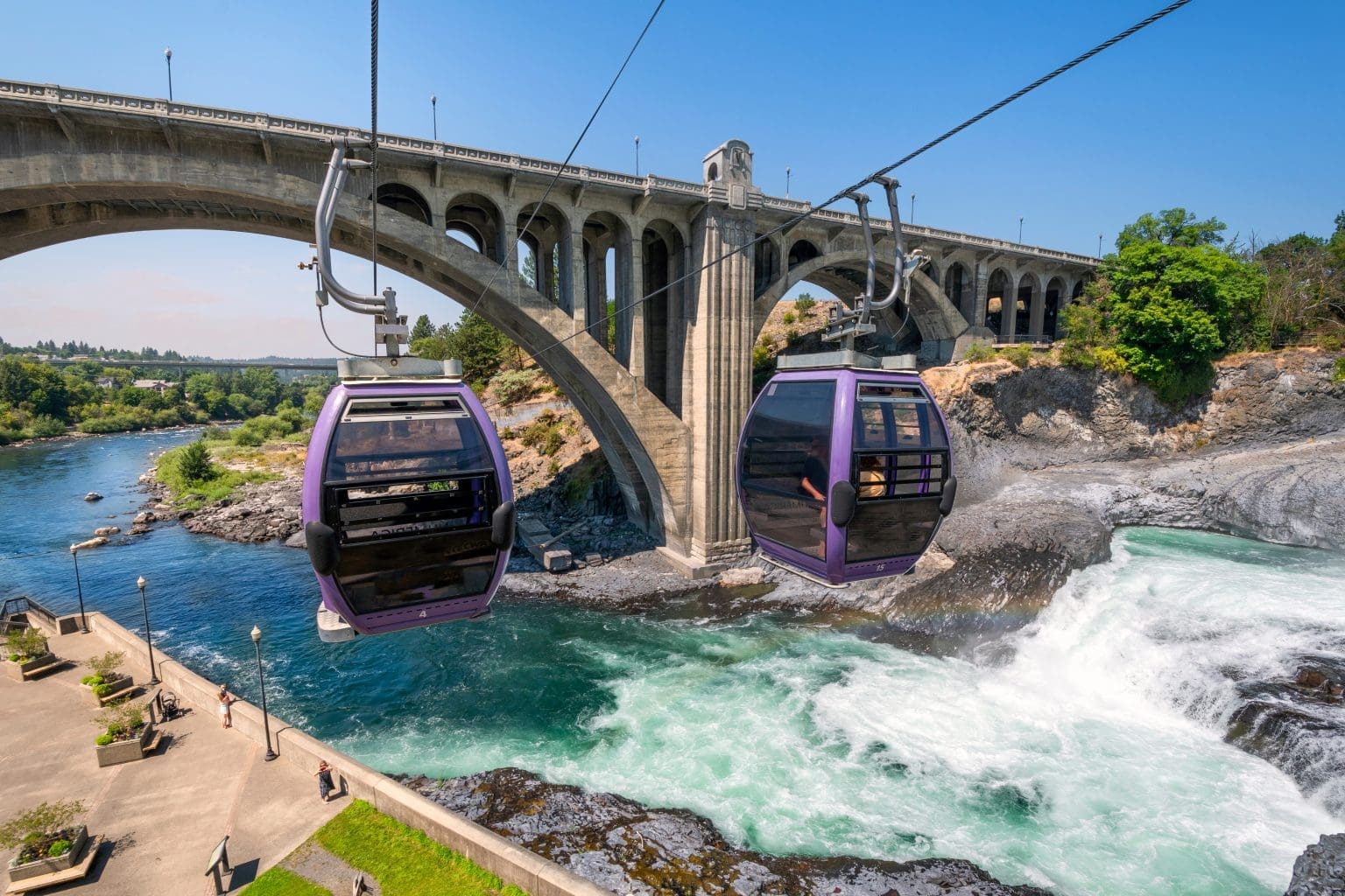 Two gondolas fly over the Spokane River and falls near Riverfront Park on a summer day in Spokane, Washington, USA